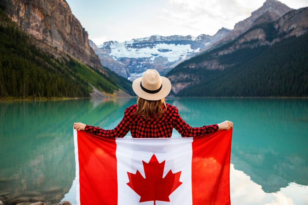 pexels-photo-2916828-2916828 Woman holding a Canadian flag at stunning Lake Louise, Alberta, embracing nature and patriotism.